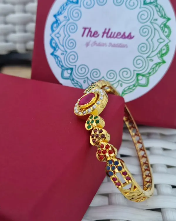 A side view of the "Ada" gold-plated Jadau bracelet. This angle highlights the colourful stones set in heart-shaped designs along the band.