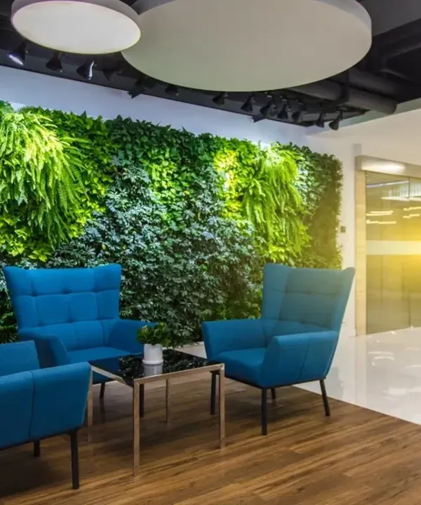 A lush vertical garden creates an extraordinary first impression in this modern office lobby. The vibrant green wall contrasts beautifully with the contemporary furniture, establishing a sophisticated and nature-inspired corporate identity.