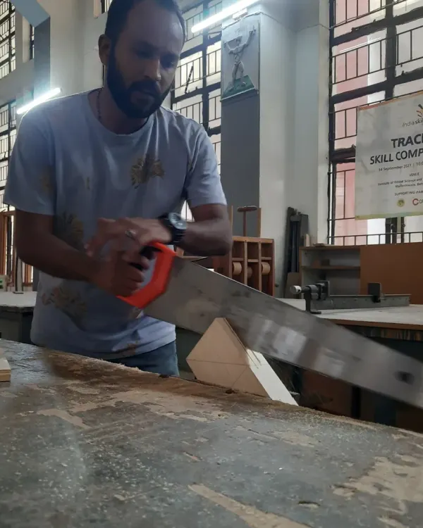 A student practices a fundamental skill, using a hand saw to make a precise cut. Mastering hand tools builds an intuitive understanding of how wood behaves.