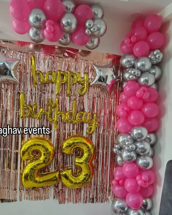 A beautiful wall decoration for a 23rd birthday. This setup features a pink and silver balloon arrangement, a rose gold shimmer curtain, 'Happy Birthday' foil letters, and large number '23' foil balloons.