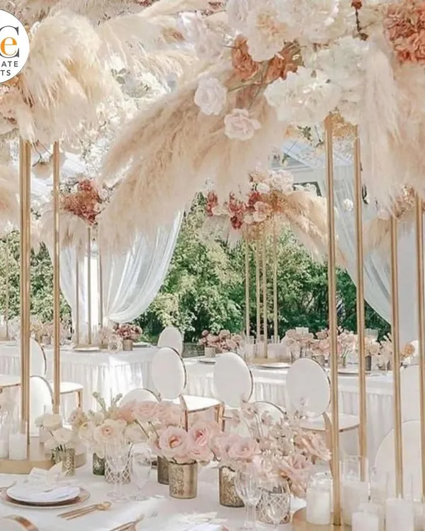 A breathtaking dining setup featuring tall centerpieces with pampas grass and white roses. This creates a sense of height and drama, perfect for a luxurious wedding reception.