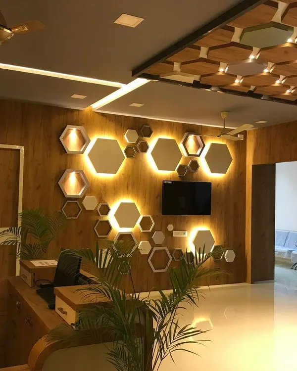 The reception of the Jeevannavar Skincare Clinic features a striking wall of backlit hexagonal mirrors and panels. This geometric design, combined with warm wood tones, creates a professional and stylish first impression.