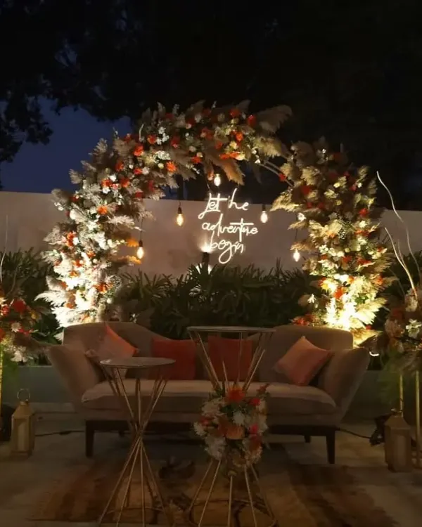A breathtaking floral arch creates the perfect focal point for this outdoor engagement party. The design uses a mix of dried pampas grass and fresh flowers, with a neon sign to celebrate the couple's new beginning.