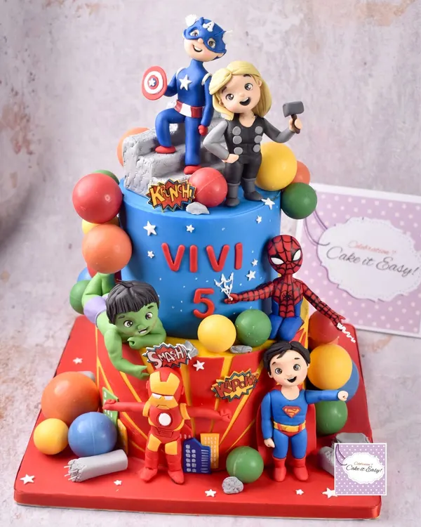 Assembling the Avengers! This cake was a huge project, taking four days to create all the handmade figurines and decorations. Every detail, from the chocolate balls to the hand-painted speech bubbles, was crafted to create a playful and action-packed scene.