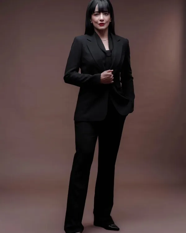 A powerful and professional full-length portrait. The clean, solid background and classic power suit create a look of authority and confidence, perfect for a corporate or executive profile.