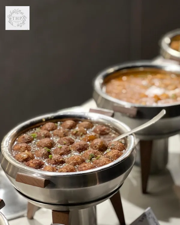 A close-up of our delicious Veg Manchurian, served hot in a modern stainless steel chafing dish. It's a perfect addition to any multi-cuisine menu for your wedding or party.