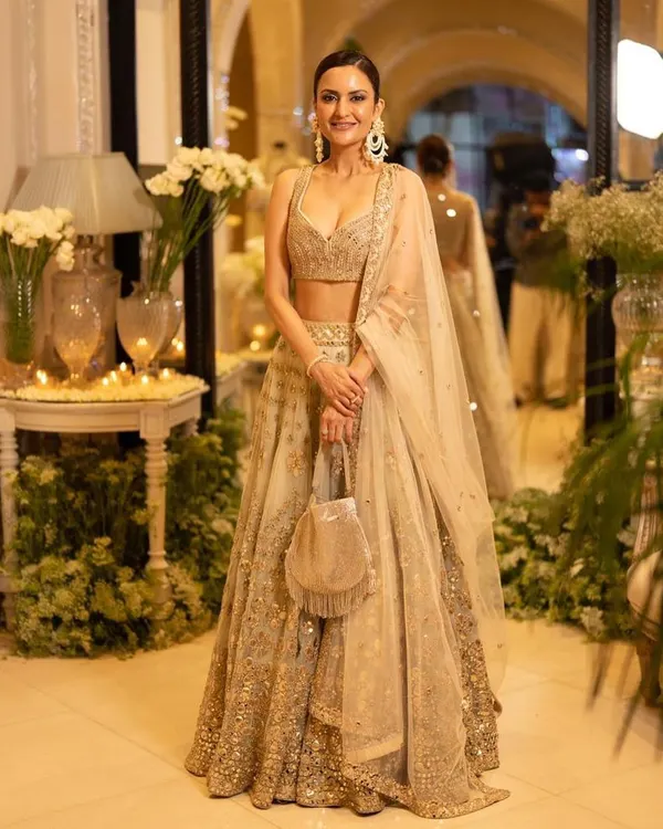 A full-length view of a client styled for a designer store launch, looking radiant in a golden lehenga. We created a sophisticated look with a clean bun and luminous makeup to match the elegance of the event.