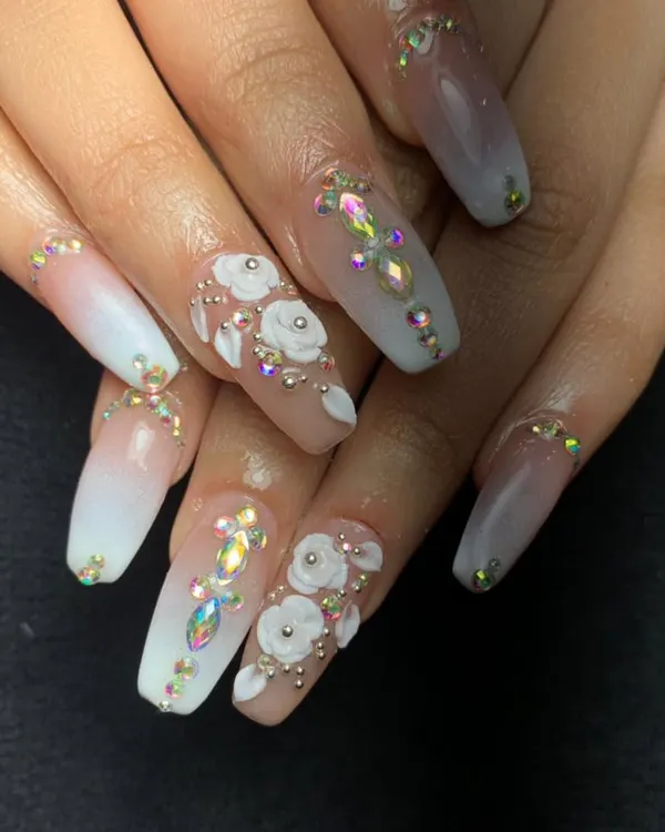 An absolutely stunning bridal look with long, square-shaped acrylics. This set features a white ombre base, intricate 3D white roses, and a lavish placement of iridescent Swarovski crystals.