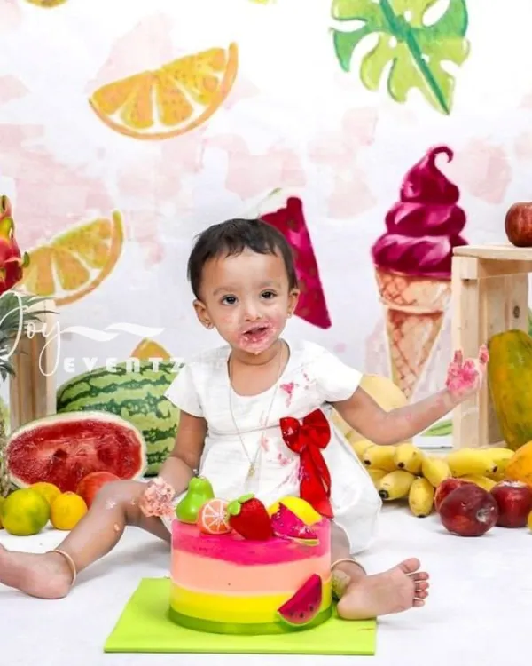 A vibrant and healthy twist on the classic cake smash. This fruit-themed session features a baby enjoying a colorful cake surrounded by fresh pineapples, watermelons, and other tropical fruits for a fun and unique first birthday shoot.