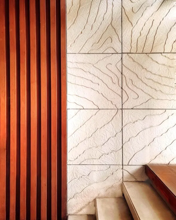 Our philosophy is that art takes nature as its model. This detail shot shows our custom wall art, where we contrasted the linear pattern of Burma Teak wood with an abstract organic design carved into Mint Gwalior stone, inspired by the veins of a leaf.