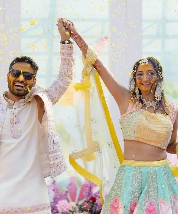A golden beginning for a beautiful journey. This couple's Haldi was a burst of sunshine and celebration, and this shot captures their triumphant joy as they are showered with blessings and flower petals.