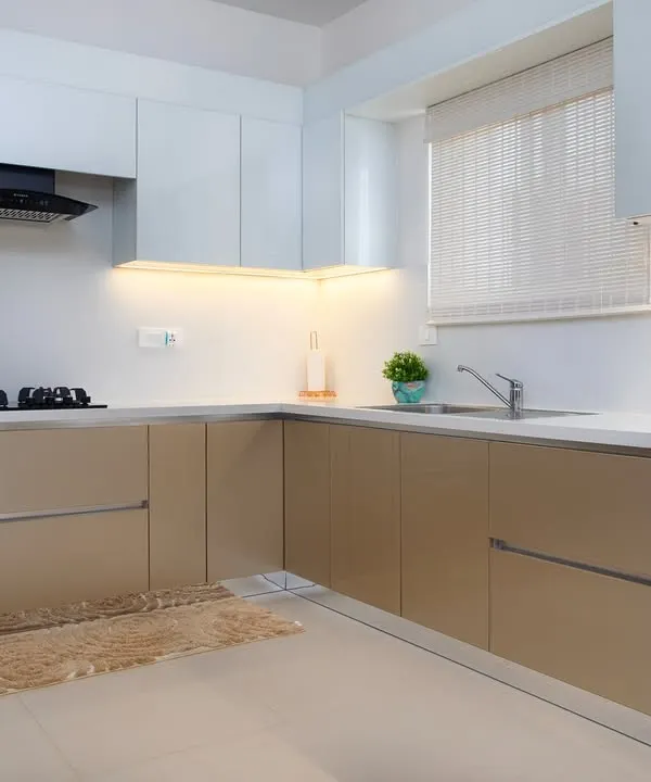 A full view of this L-shaped kitchen, where high-gloss beige lower cabinets are paired with matte white uppers. This combination creates a subtle contrast in texture and finish, adding depth to the neutral color scheme.