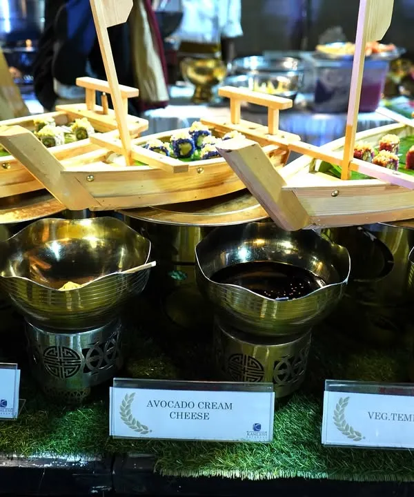 A creative presentation for our vegetarian sushi station. The sushi, including Asparagus Bell Pepper and Avocado Cream Cheese rolls, is served in miniature wooden boats, making the experience visually delightful and unique.