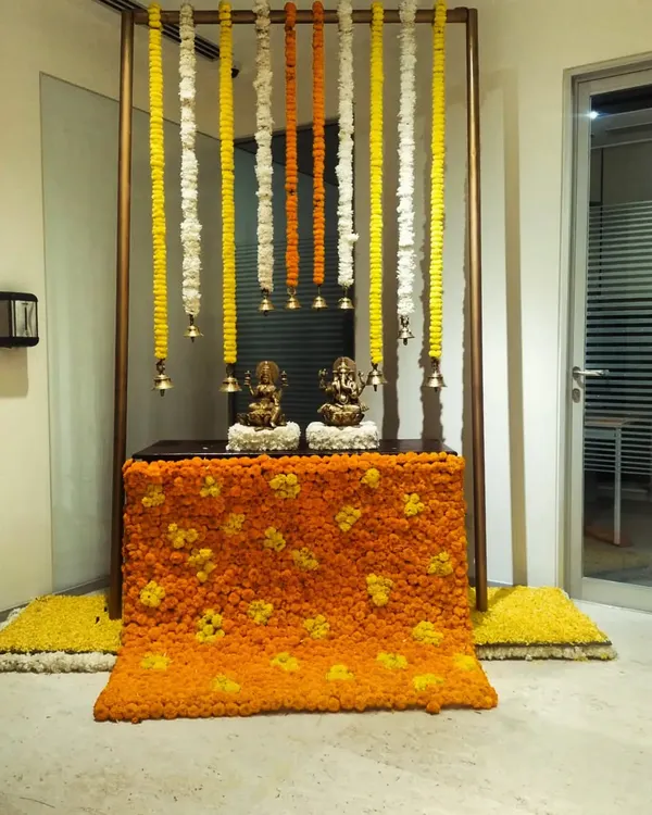 For a corporate Diwali celebration, we designed this sacred corner featuring idols of Ganesh and Lakshmi. The setup includes a backdrop of hanging marigold and tuberose garlands and a base covered in a floral carpet.