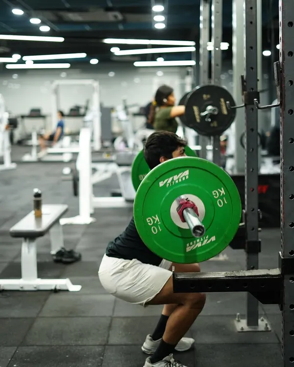 A member executes a heavy squat in the rack, a foundational exercise for building lower body strength and power. The focus and determination are clear.