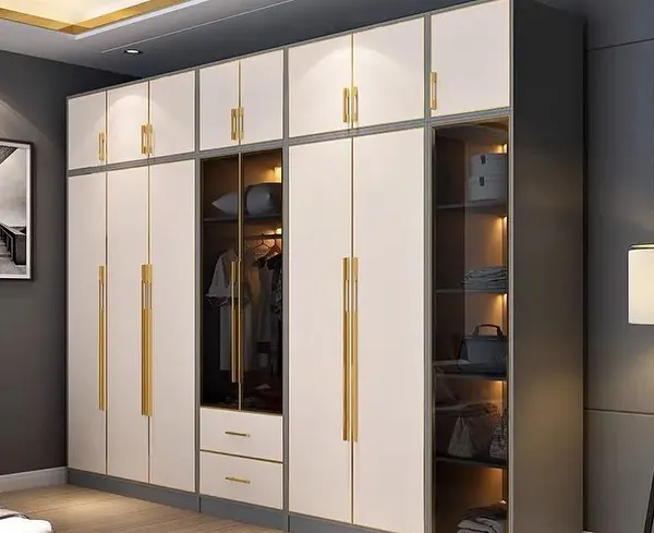 A floor-to-ceiling wardrobe in white and gold, featuring a mix of closed cabinets, drawers, and a glass display section. This design offers extensive storage while adding a touch of luxury to the bedroom.
