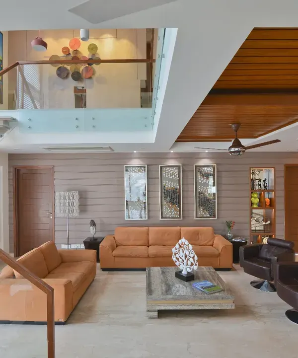 The drawing room of the Sobti Residence is characterized by a striking double-height volume. Abundant natural light enhances the openness of the space, while a floating wood-and-glass staircase adds architectural elegance.