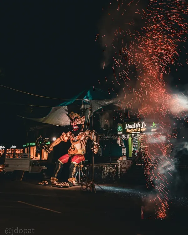 A giant effigy of the demon Narakasura stands on a Goan street during Diwali, with sparks from a firecracker flying in the foreground.
