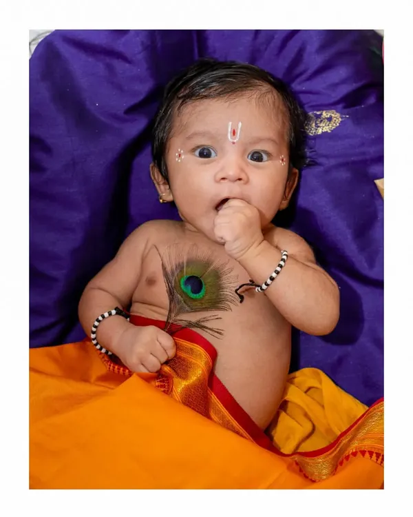 An adorable baby portrait from a Janmashtami themed shoot. This little 'Kanha' with his wide-eyed expression and a peacock feather is a perfect example of a creative and memorable baby photoshoot.