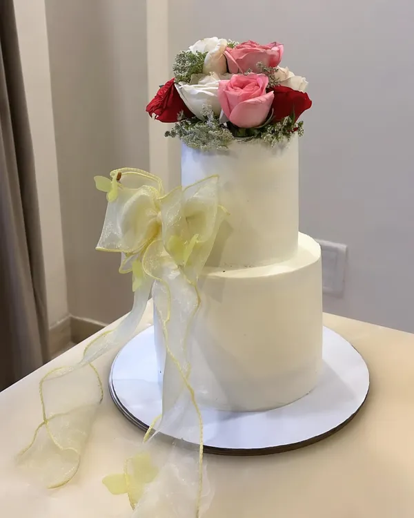 A two-tiered cake inspired by the elegance of Bridgerton. The bottom tier is Salted Caramel & Almond, and the top is Mango & White Chocolate, all enrobed in smooth vanilla buttercream.
