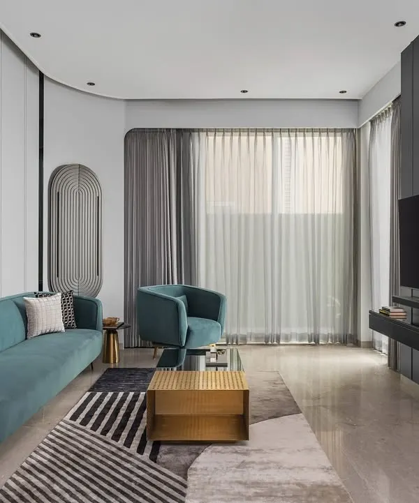 This living room from our 'Charcoal Chateau' project balances bold color with minimalist design. The vibrant teal sofa creates a striking focal point against the clean white paneling and geometric rug, crafting a space that is both sophisticated and welcoming.