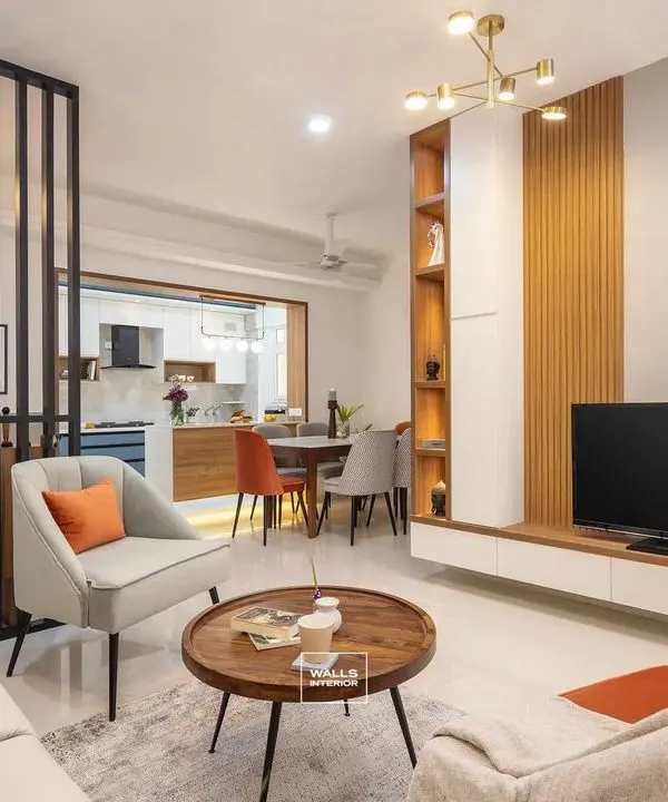 A welcoming and bright living room that showcases an open-plan design connecting to the dining area. We used a modern aesthetic with clean lines, a wooden-paneled TV unit, and pops of orange in the decor to create a warm, inviting atmosphere.
