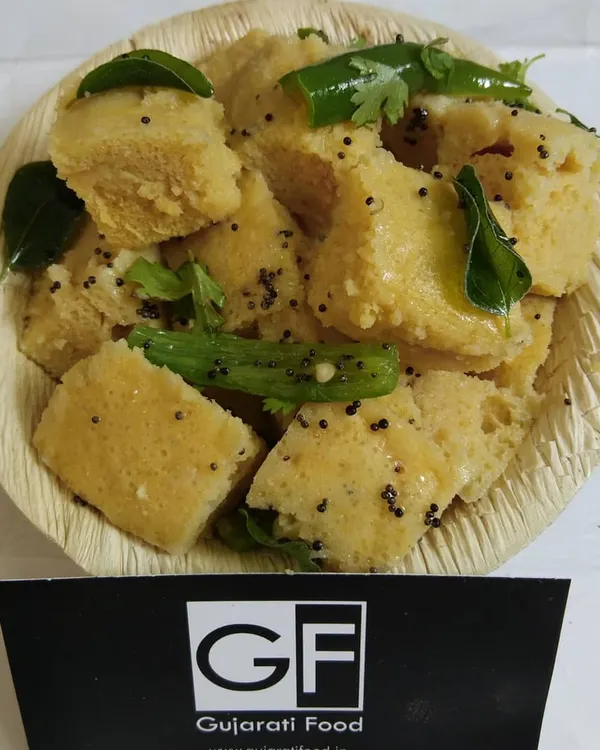 This is my soft and spongy Khaman, garnished with mustard seeds, curry leaves, and green chillies. It's a light and savory steamed snack that is a favorite for breakfast or tea time.