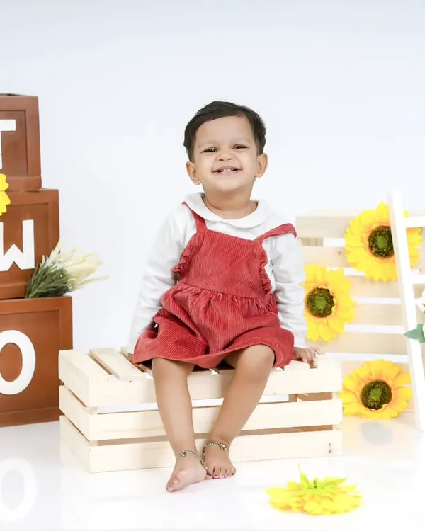 Celebrating the "Terrific Twos"! This little girl's bright smile is the centerpiece of her second birthday photoshoot, complete with "TWO" blocks and sunflowers.