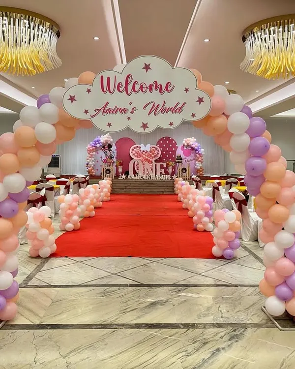 A grand entrance for a first birthday, creating a 'wow' factor right from the start. A massive balloon arch leads guests down a red carpet to the main stage, setting the scene for a spectacular event.