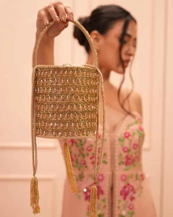 This classic gold potli bag is a must-have for your ethnic wardrobe. The intricate diamond-studded craftsmanship and elegant tassels make it a versatile accessory for any traditional outfit.