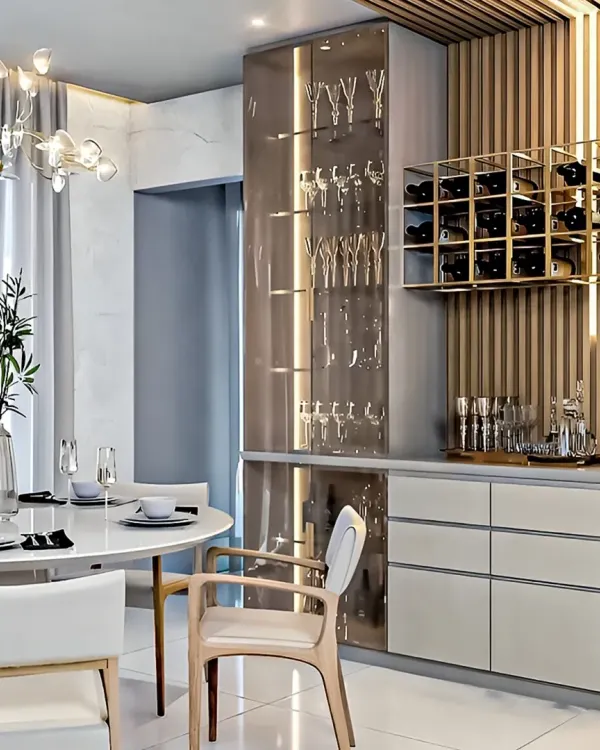 This modern dining area features a custom bar unit we designed. It includes a tall, illuminated glass cabinet for stemware, handle-less drawers, and a wall-mounted gold wine rack against a fluted wood panel.