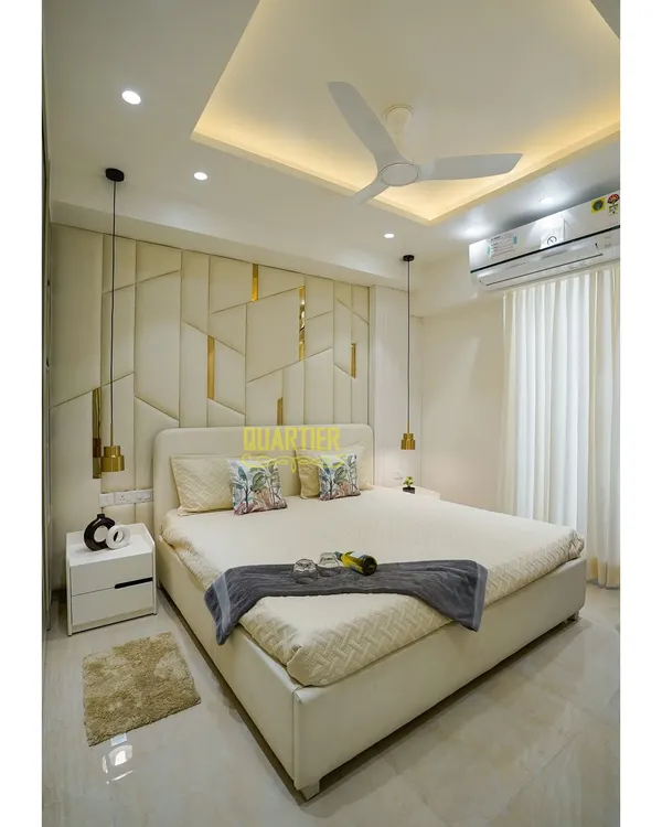 This master bedroom at Tata La Vida, Gurugram, is the epitome of serenity. The full-height upholstered headboard features an asymmetrical geometric pattern with gold metal inlays, creating a stunning and luxurious focal point.