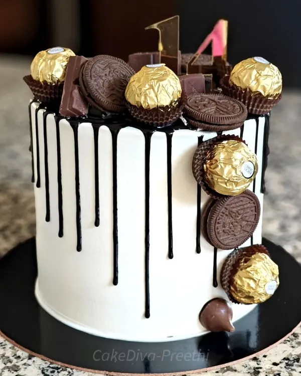 A little too much chocolate is just about right! This tall drip cake is frosted with white buttercream, has a rich black chocolate drip, and is loaded with Ferrero Rochers, Oreos, and chocolate bars.