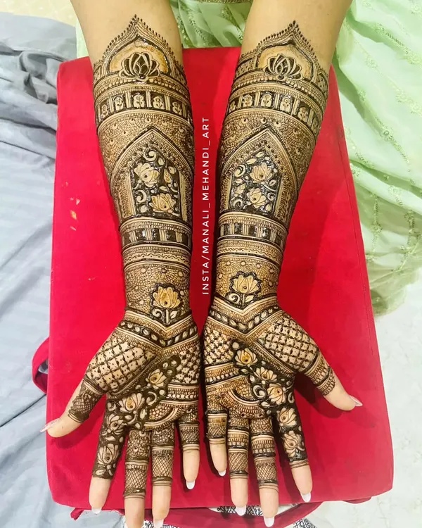 This full-arm design features classic palace-style arches and delicate lotus motifs. The intricate line work and symmetrical patterns create a look of pure elegance for the bride.