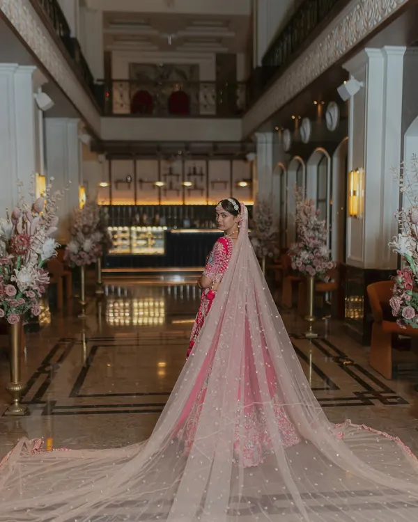 A stunning portrait of the bride, her long, elegant veil spread out behind her in a grand hotel lobby. This shot is all about drama and elegance.