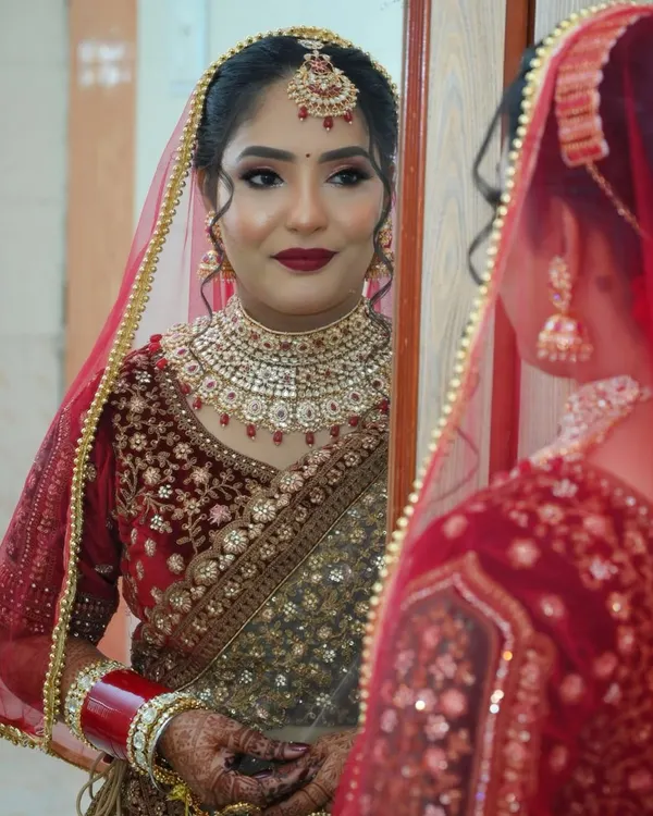 A quiet moment of reflection for the bride before she steps into her new chapter. This classic red and gold bridal makeup is designed to be both bold and elegant, perfectly complementing her traditional attire.