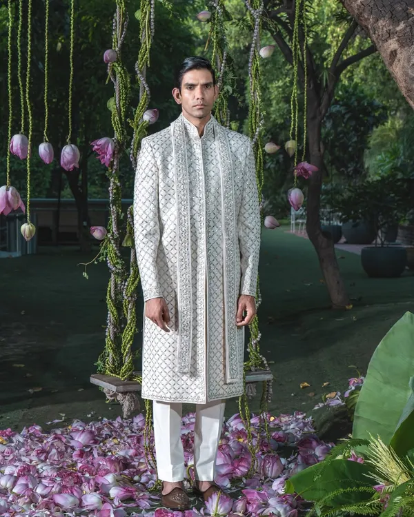 This immaculate ivory sherwani, detailed with subtle geometric embroidery, embodies regal elegance. It is a testament to our four decades of heritage, crafted for the groom who seeks a timeless statement of sophistication on his wedding day.