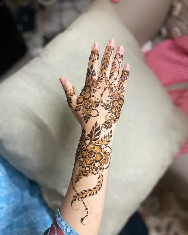 A classic Arabic henna design featuring a floral vine that gracefully trails from the wrist down to the index finger.