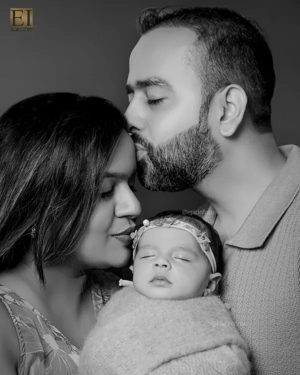 A tender black and white portrait of new parents embracing their sleeping baby. This style emphasizes the raw emotion and love in the moment.