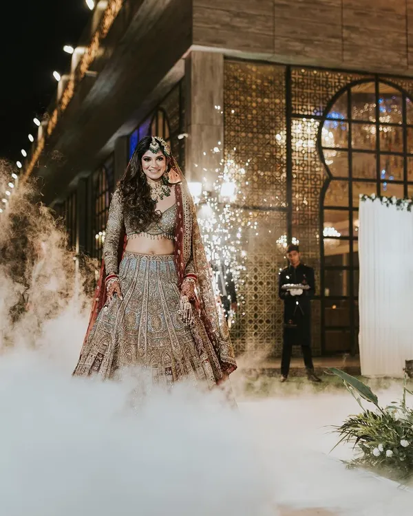 A grand bridal entry. The makeup is designed to be dramatic and visible, ensuring the bride is the center of attention in this smokey, cinematic shot.