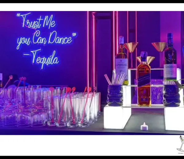 Let the bar do the talking. A neon sign with a fun quote like 'Trust Me you Can Dance - Tequila' instantly sets a playful, high-energy tone for a sangeet or cocktail party.