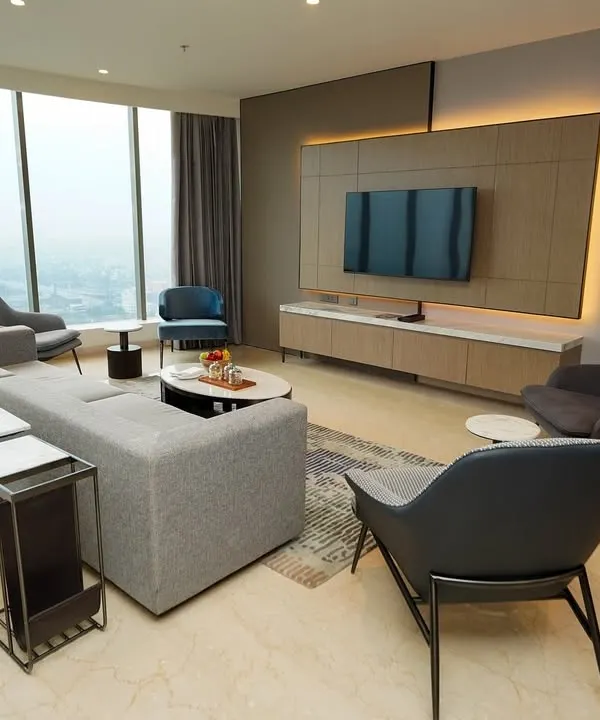 The main living area of a modern apartment, emphasizing the spacious layout and floor-to-ceiling windows that offer a panoramic city view. This shot is designed to sell a lifestyle of urban luxury.