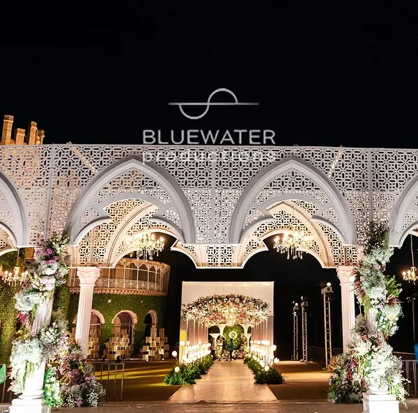 A wide-angle view of our 'Blue Palace' reception stage, showcasing the grand scale of the custom-fabricated white arches against the historic Bangalore Palace venue.