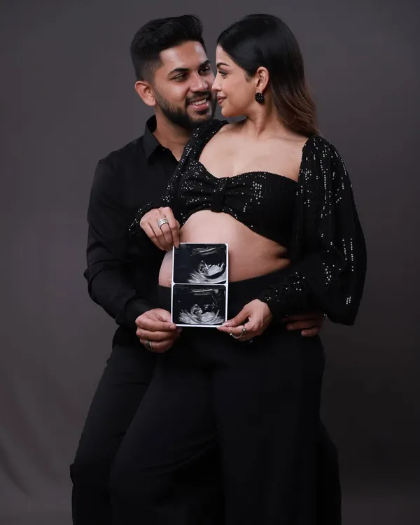 The first look at your little one. This couple proudly holds up their sonogram pictures, a classic and heartwarming way to announce their pregnancy during their modern studio shoot.