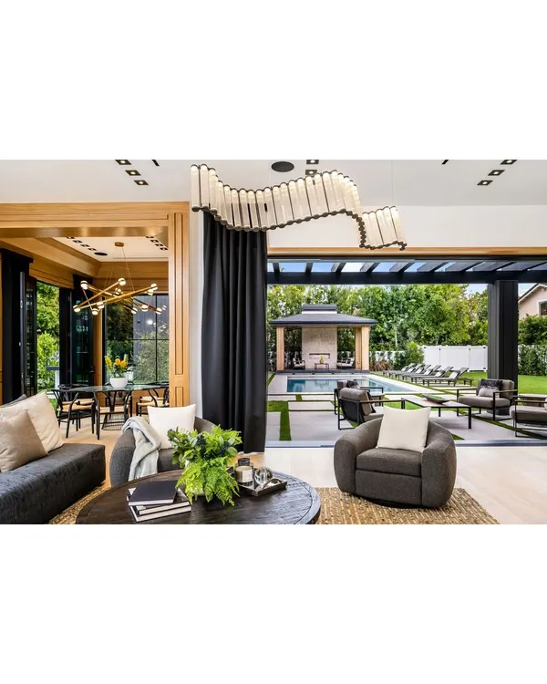 We specialize in creating seamless indoor-outdoor living experiences. This space features expansive sliding glass doors that open up the living area to a beautiful patio and pool, perfect for entertaining or quiet relaxation. The design emphasizes natural light and a connection with the outdoors.