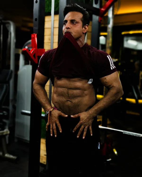 The result of discipline. This client is showing off his well-defined abs after a workout. A lean physique like this is achieved with a combination of a strict diet plan and consistent ab exercises.