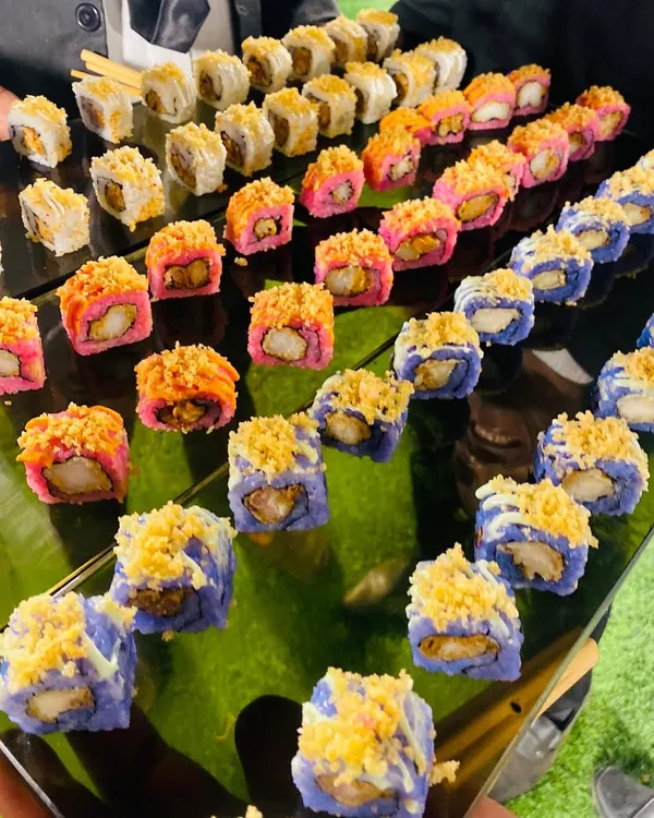 A vibrant platter of assorted sushi rolls, showcasing a beautiful mix of colors, textures, and flavors. From pink and blue rice to crunchy tempura toppings, each piece is a work of art.