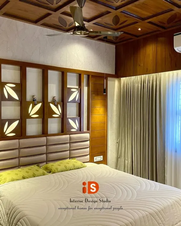 This traditional master bedroom is a showcase of exquisite woodwork. It features a custom-designed headboard with backlit leaf motifs and a stunning coffered ceiling made from polished wood, creating a warm and luxurious ambiance.