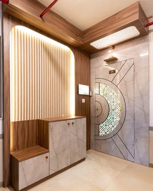 This grand entryway makes a statement with a marble-finish door featuring a geometric pattern, paired with a fluted wood panel wall and integrated seating and storage.