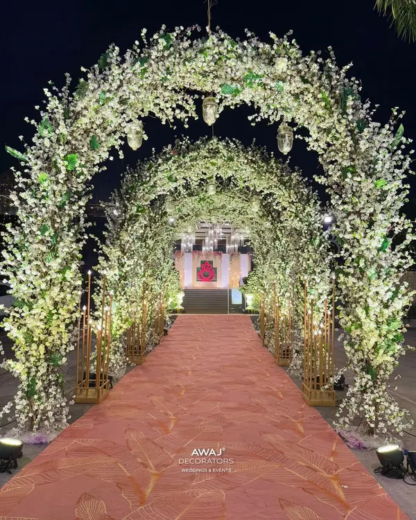 A fairytale entrance tunnel made of white cherry blossom branches, creating a magical, starlit path for guests to walk through.